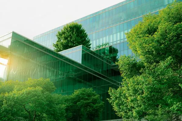 a glass corporate building surrounded in lush trees