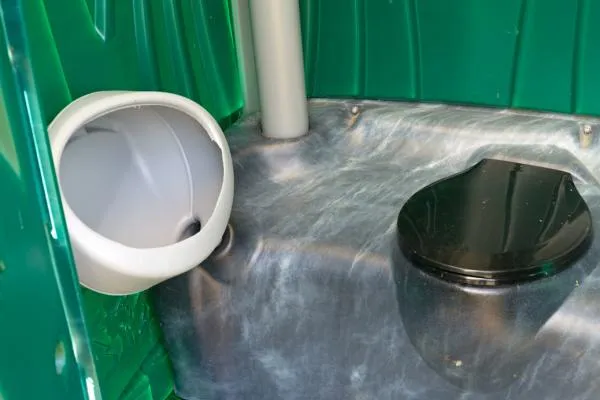 inside a green porta potty with toilet and urinal