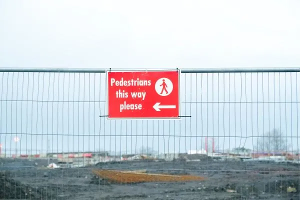 red pedestrian sign on temporary fencing around construction site