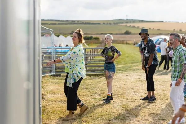 smiling people at a festival waiting in line for portable toilets