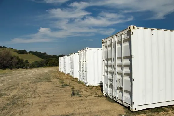 four white storage containers near a green hill