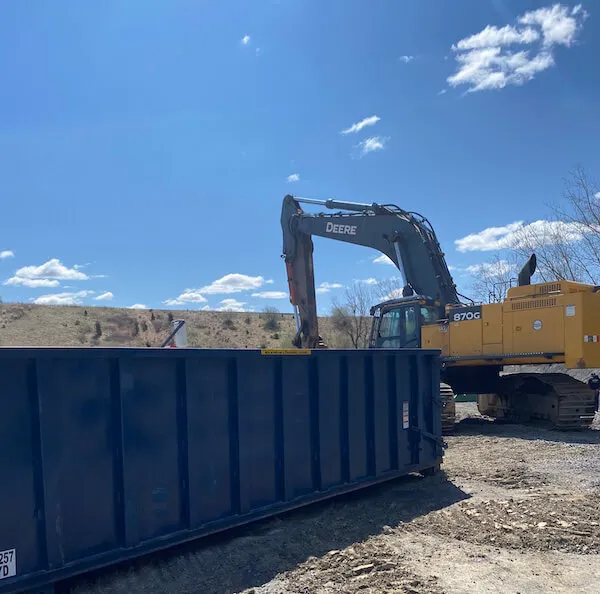 An excavator loading a 30 yard dumpster in Anne Arundel County MD