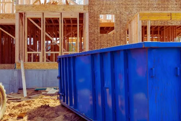 blue dumpster in front of home under construction