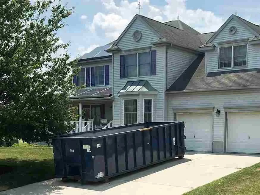 picture of a dumpster in driveway of grey house