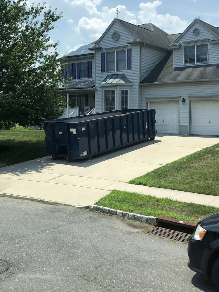 A 30 dumpster in a driveway in front of a grey house in Camden County NJ