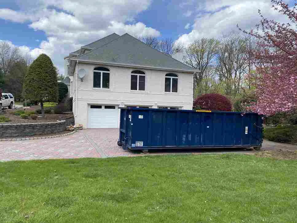Roll off bin on pink driveway in front of house