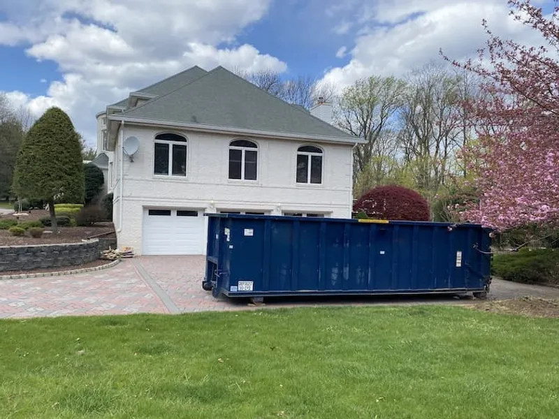 A blue 30 yard dumpster on a paver driveway