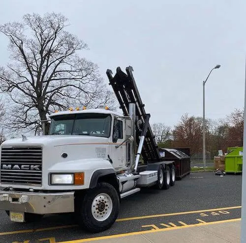 Roll-off truck picking up a dumpster in a parking lot