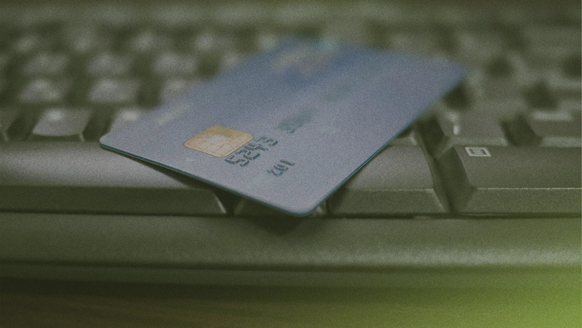 A credit card with a chip rests on a computer keyboard, symbolizing online transactions.