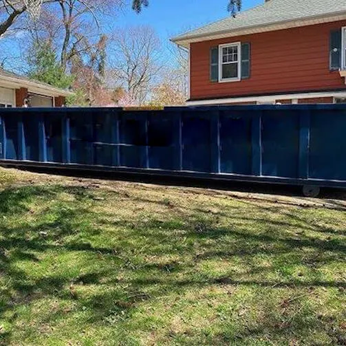Blue roll off bin in front of house