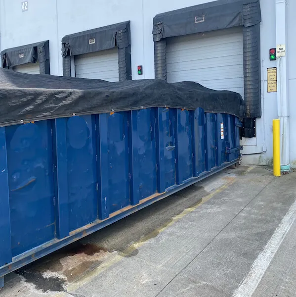 A roll-off dumpster with a tarp over it in front of a loading dock in the state of Georgia