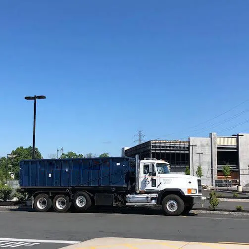 Image of roll off bin truck driving down the  street 
