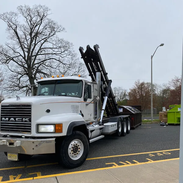 Roll off truck picking up a dumpster in a parking lot in Lacakawanna County PA