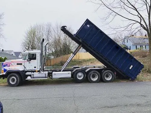 Roll off dumpster being rolled off truck