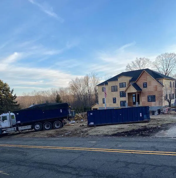 A roll off truck with two 30 yard dumpster rentals in front of a house being built