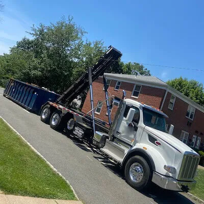 Roll-ff truck with 30 yard dumpster being delivered next to an apartment building