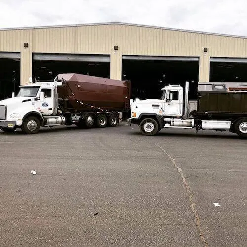 Two roll off trucks with dumpsters at a disposal facility