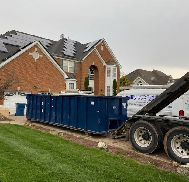 30 yard dumpster being delivered to a brick house with solar panels