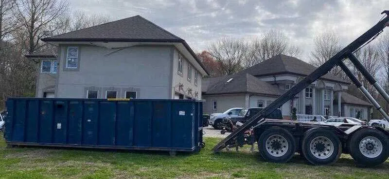 Picture of dumpster being loaded off roll off truck 