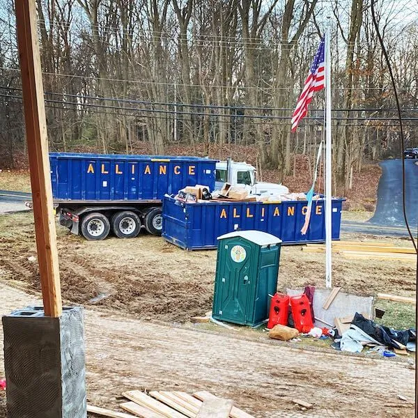 Two blue Sourgum Waste (formerly Alliance Disposal) 30 yard roll off dumpsters on a construction site