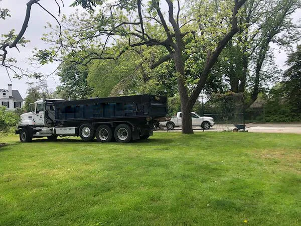 Picture of roll off bin truck on a grassy residence 
