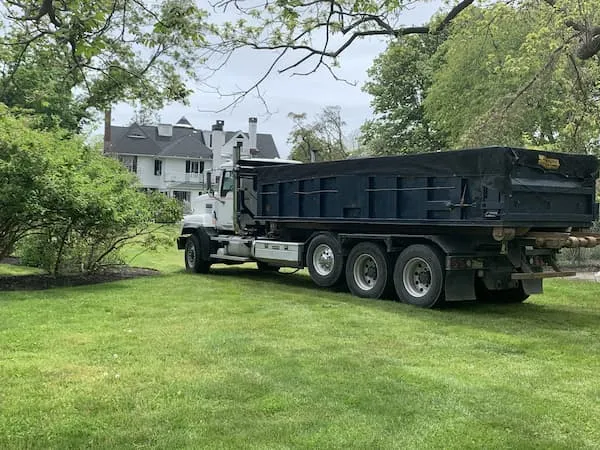 A 20 yard dumpster on a roll-off truck in a residential lawn