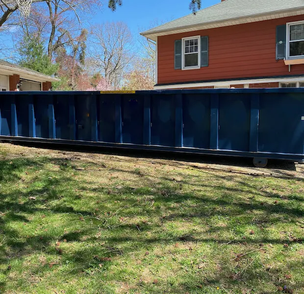 A 20 yard dumpster rental next to a red home