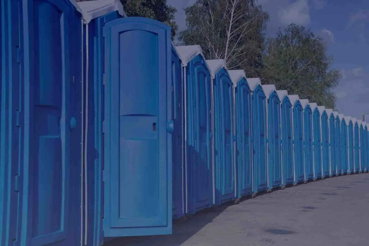 blue portable toilets lined up along a road