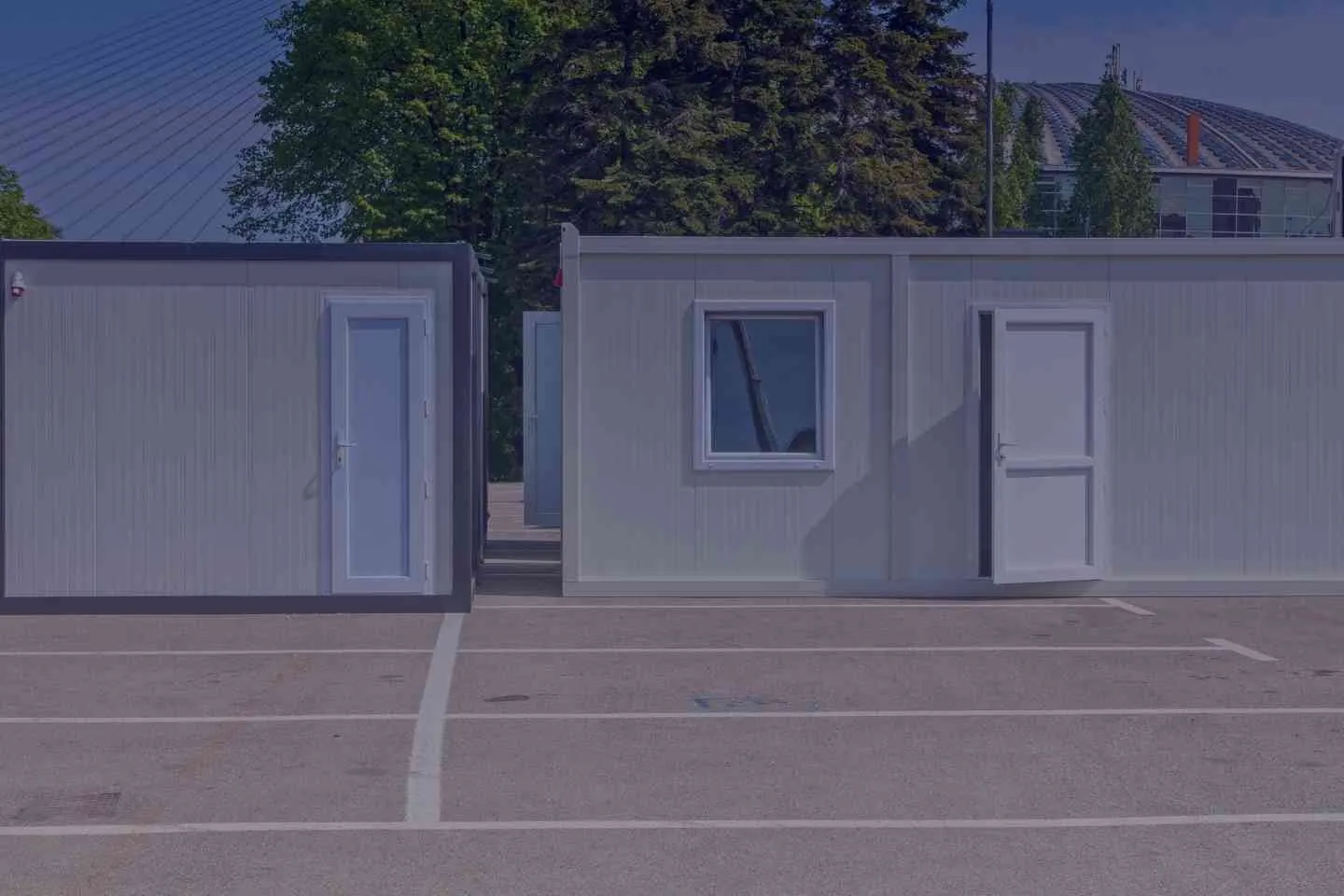 two grey storage containers used as temporary offices on a parking lot
