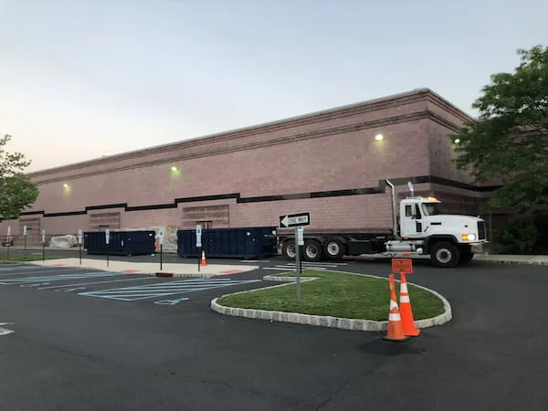 Two roll off bins outside of a warehouse