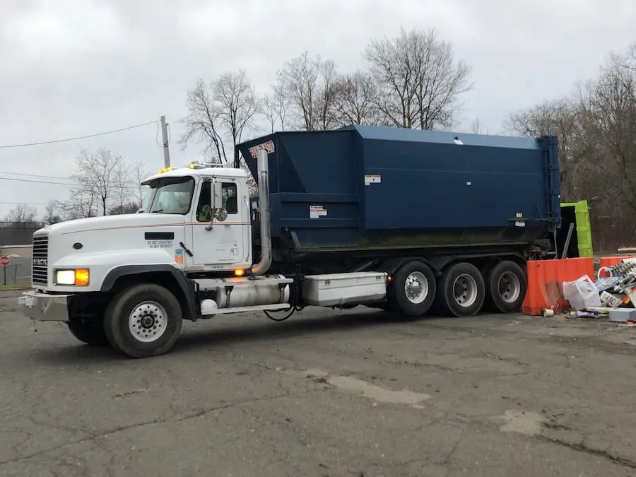 truck dropping off a compactor