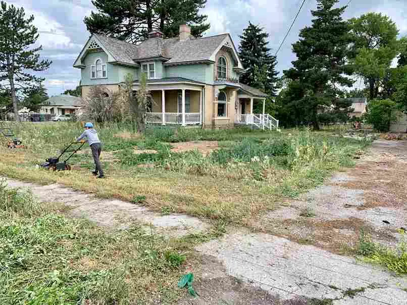 Picture of a man mowing an overgrown lawn